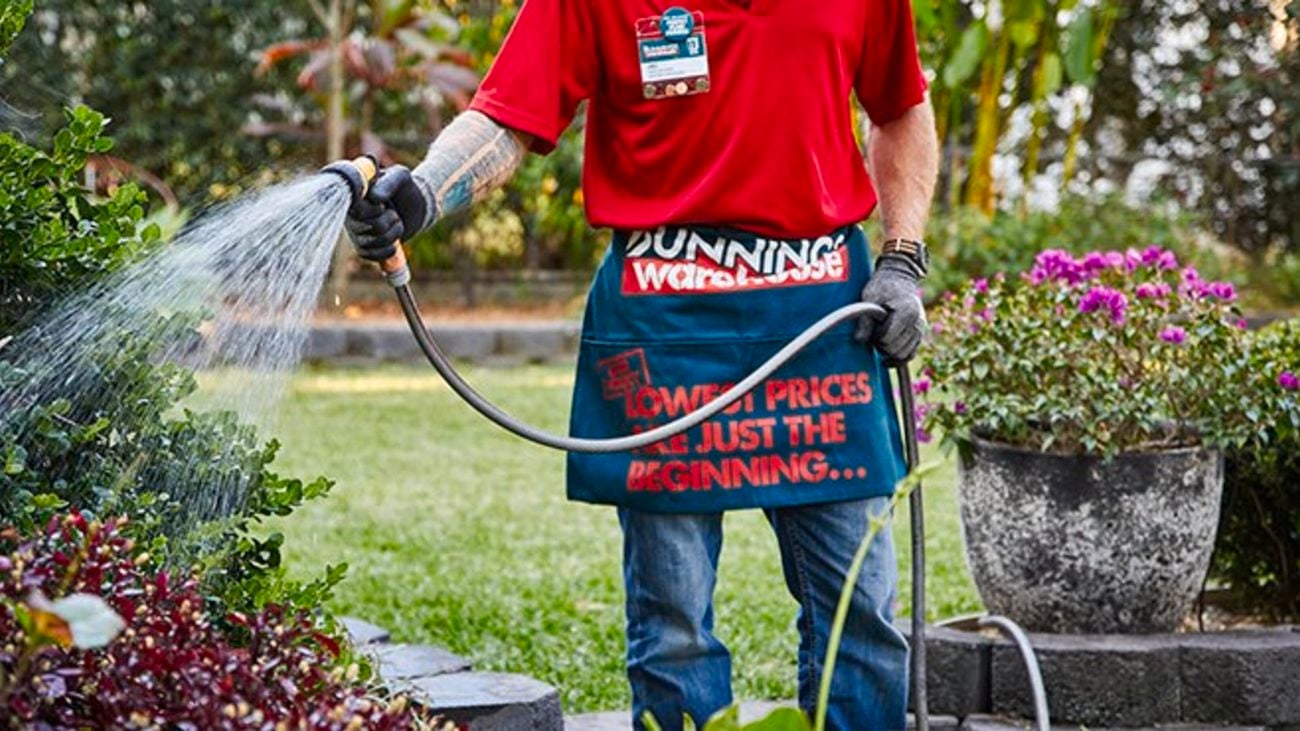 A Bunnings team member watering the garden with a hose and hose gun