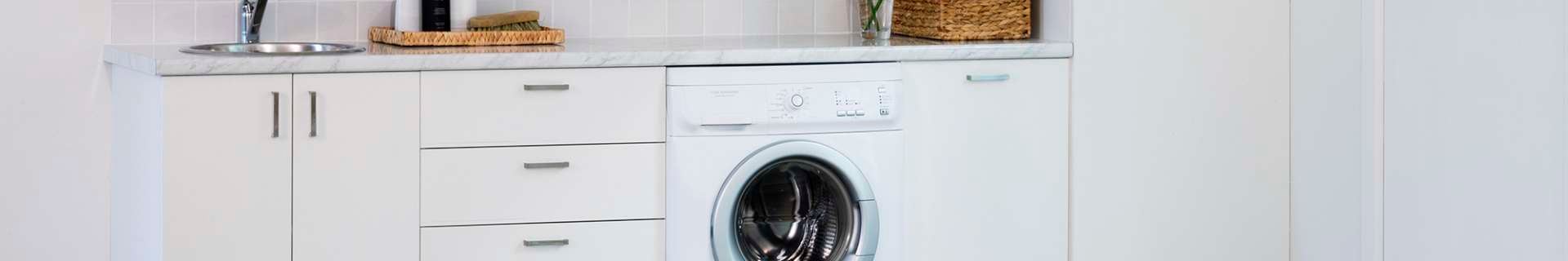 Laundry with washing machine and cupboards.