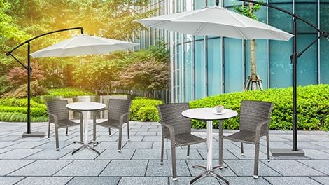 Paved outdoor area with tables, chairs and cantilever umbrellas