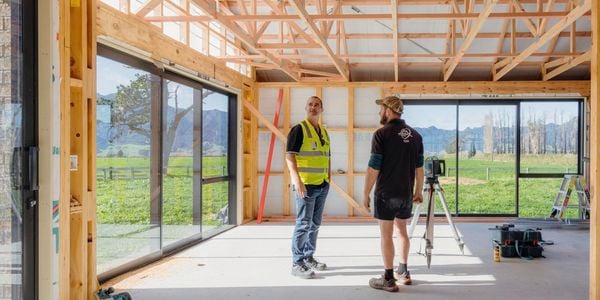 Two people standing inside a house being built