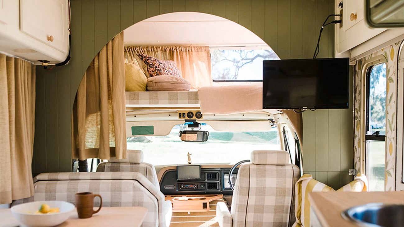 The interior of a custom RV caravan, decorated in green, plaid and timber.