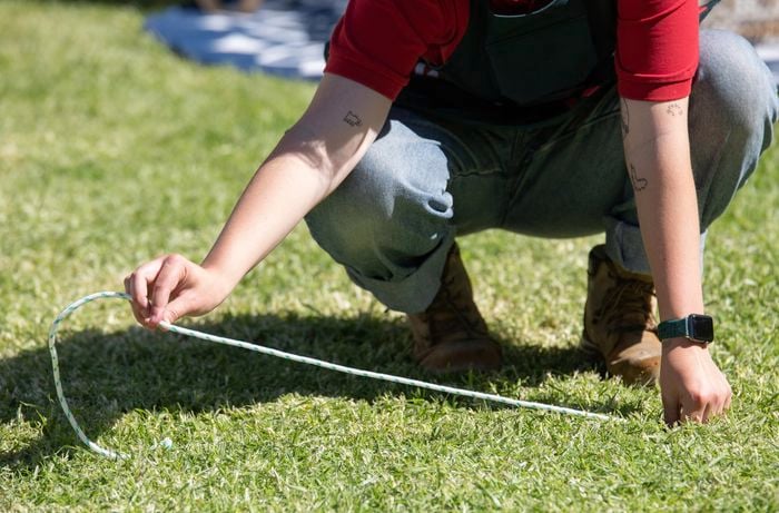 Person lining up string on the grass.