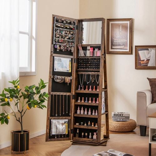 A Swivel mirror jewellery cabinet in a room with a rug on the floor, prints on the wall and a pot plant in it.
