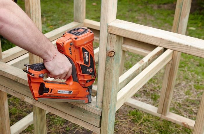 A wooden frame for a chicken coop being nailed together by a Bunnings team member with a nail gun