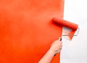 A wall being painted orange with a paint roller