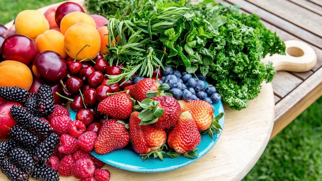 Collection of fruit on a platter board including strawberries, berries, peaches and cherries.
