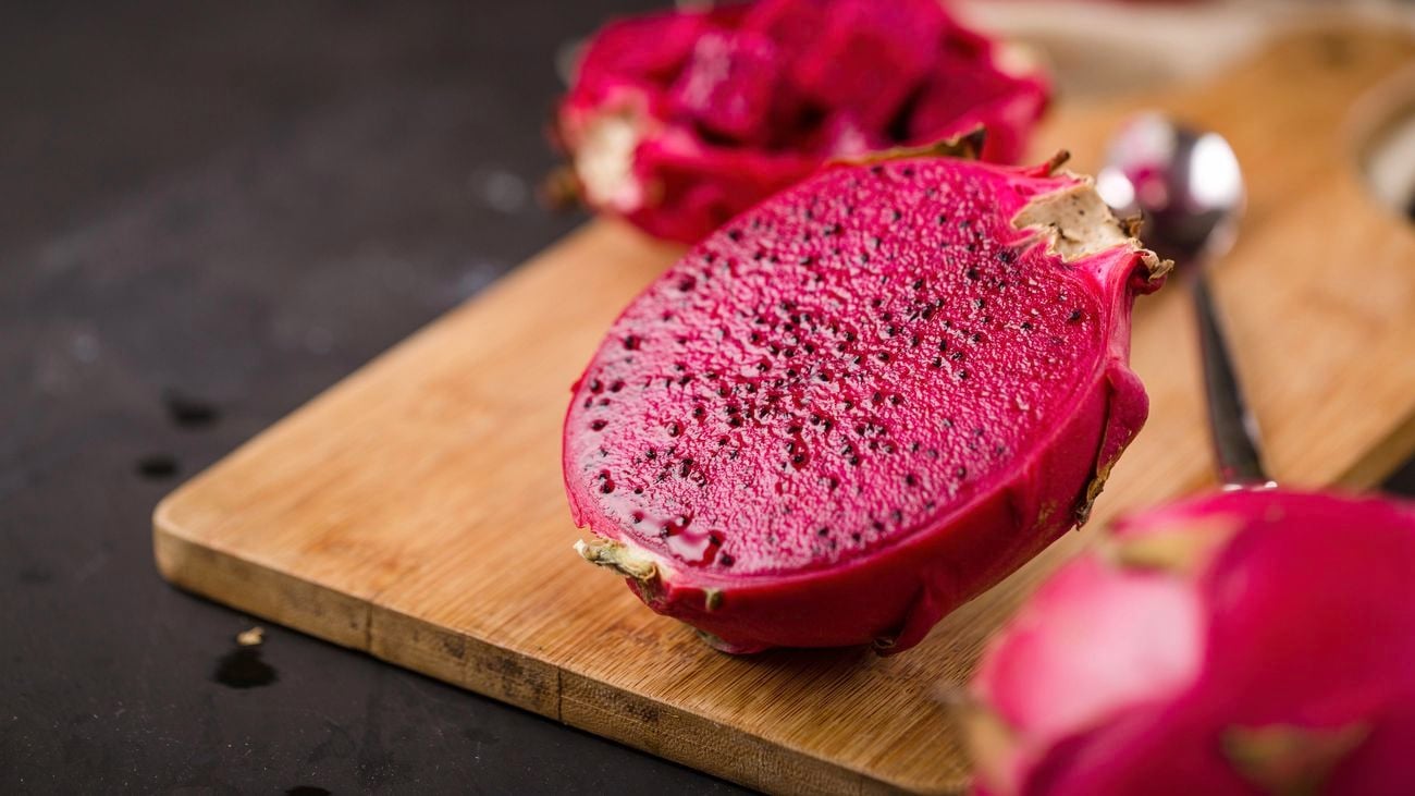 close up of a dragon fruit sliced in half on a wooden board