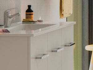 A yellow stool in front of a white vanity with an inbuilt sink in a bathroom setting