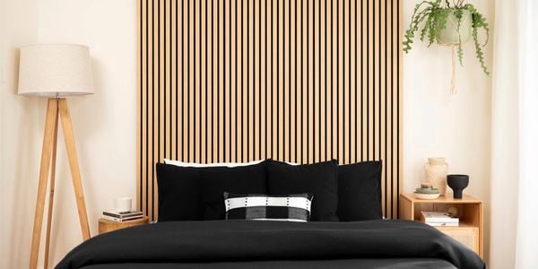 A room with floor lamp, bed and timber panels on the wall.