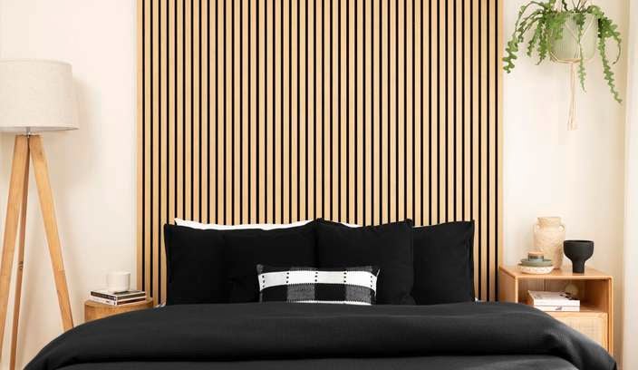 A room with floor lamp, bed and timber panels on the wall.