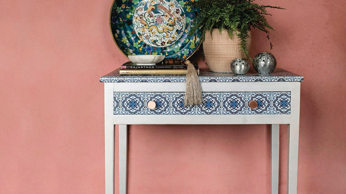 A wooden side table painted white with a Morrocan-style patterned finish