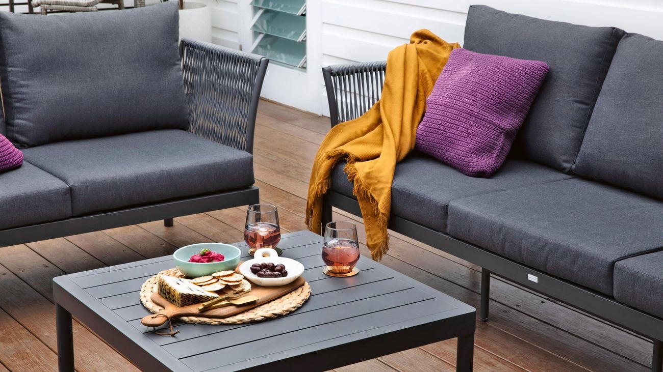Two Mimosa outdoor metal modular lounges with charcoal cushions, and a matching metal coffee table on a deck.