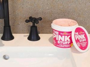 A tub of The pink stuff on a sink with black tapware.