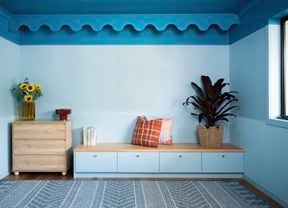 A modern room features a bold blue colour-capping design with decorative scalloped trim along the top of the wall.