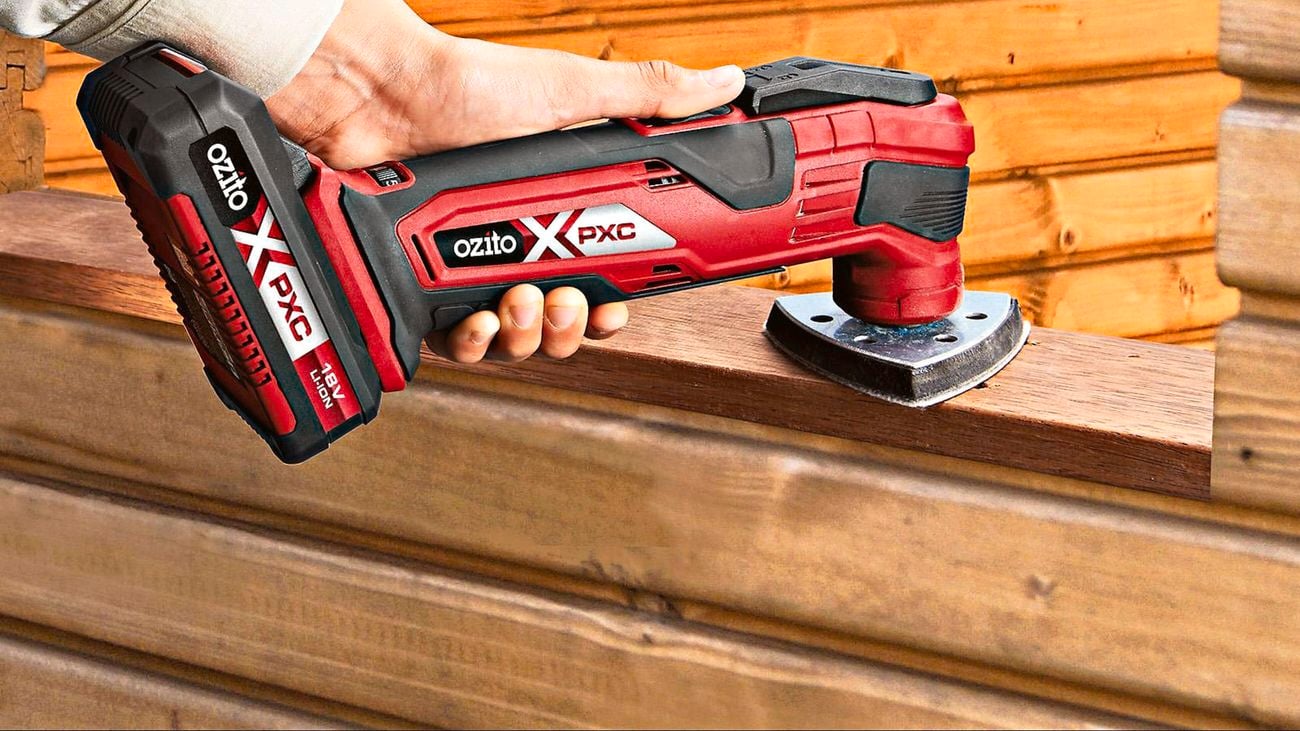 A hand using an Ozito multi function tool to sand the top of a wooden panel