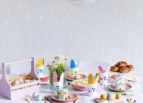 An Easter party table set up with painted eggs and hot cross buns