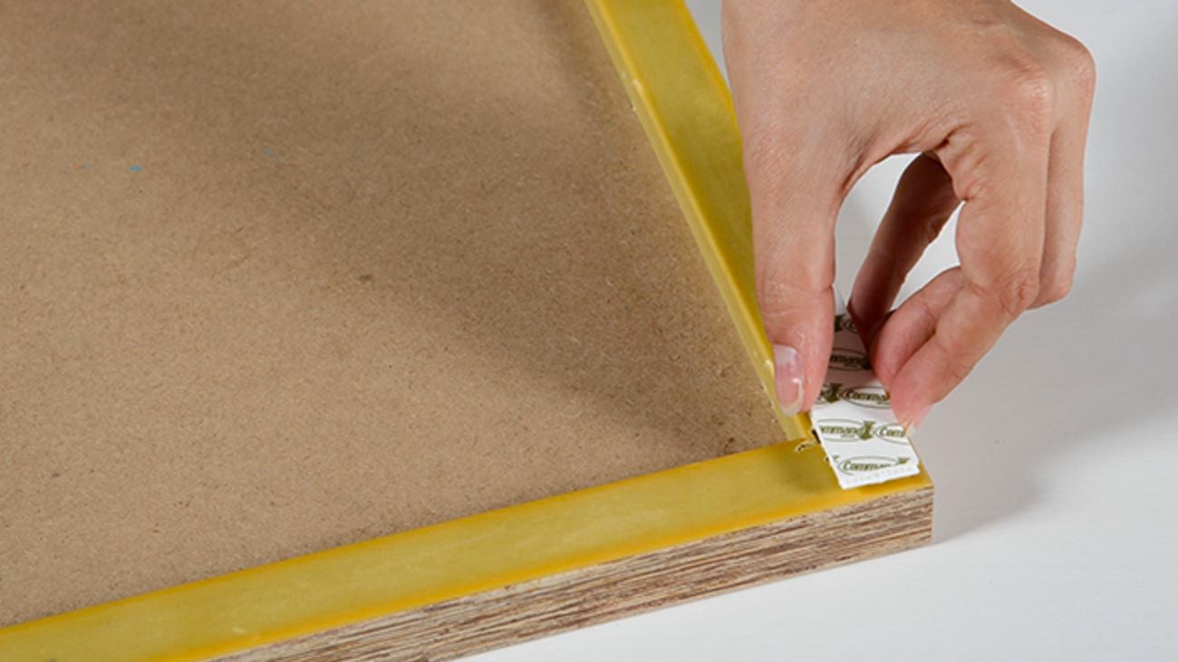 Sticking on a removable picture hanging strip to the back of a photo frame.