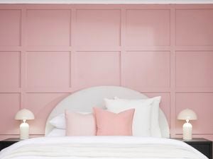 A finished bedroom featuring a pink batten feature wall behind a neatly made bed and matching bedside lamps.