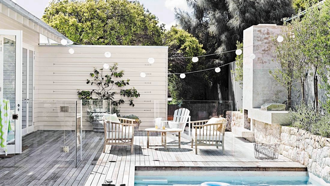 Outdoor entertaining area with deck, pool and hanging festoon lights.