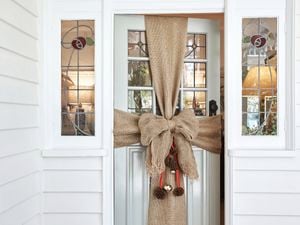 Large hessian bow wrapped like a present around the front door with pinecones and baubles hanging from the centre.