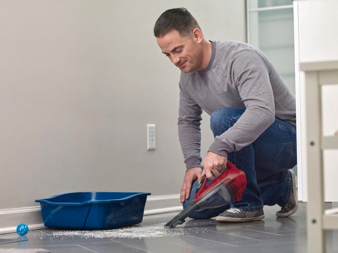 man kneeling to clean the floors with vac