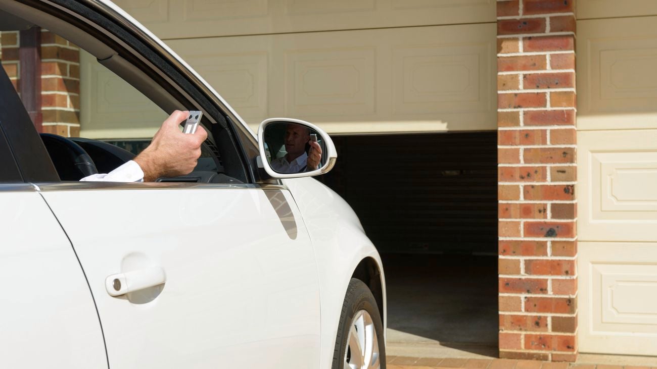 A person uses a Chamberlain garage door remote while sitting in a car