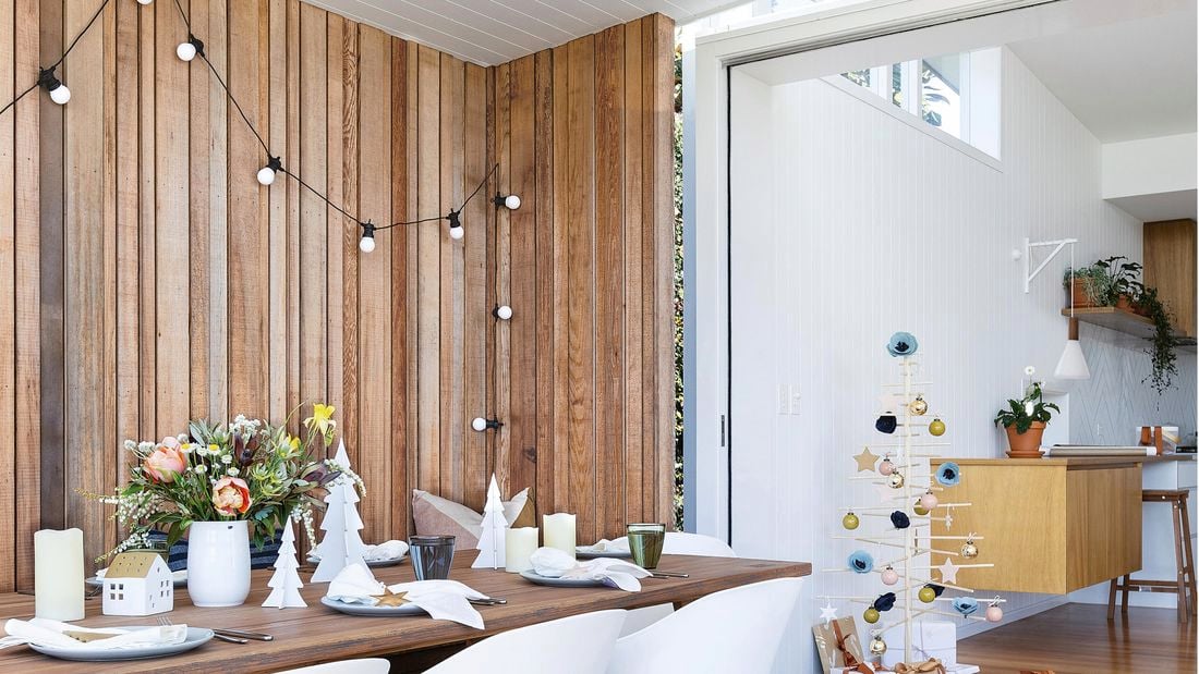 Outdoor entertaining area with table set up with dining utensils and Christmas decorations.