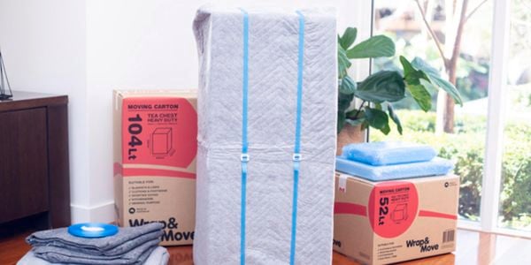 Fridge wrapped in a moving blanket and moving straps