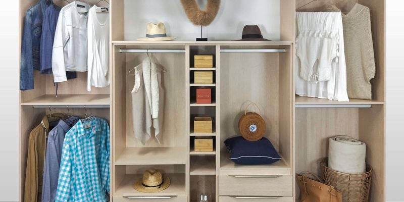 Open wardrobe with a light-coloured wood finish. In the wardrobe is an assortment of clothes, hats, bags and accessories.