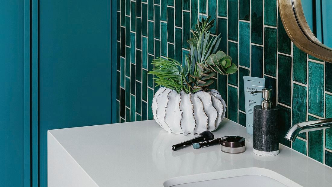 Bathroom with basin, artificial flowers, soap and mirror.