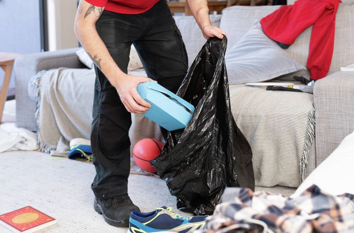 A person using a garbage bag to collect clutter during a quick home tidy-up​