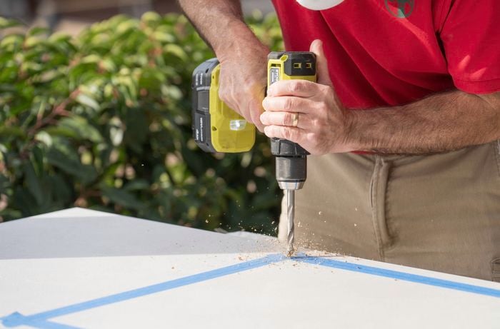  A Bunnings Team Member is drilling holes at the corner of the traced outline.