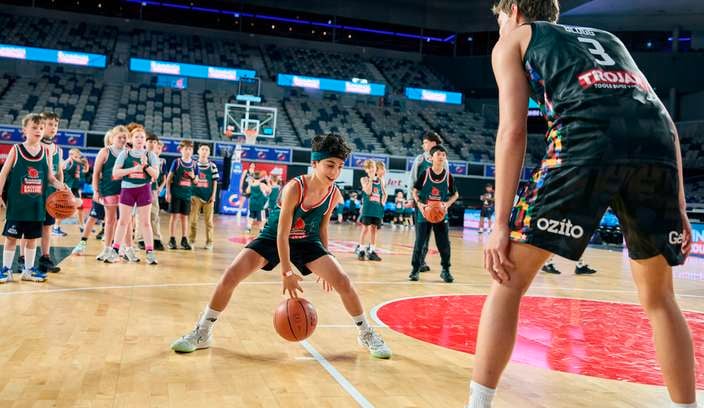 Kids in Bunnings Ballers singlets cheering in stadium