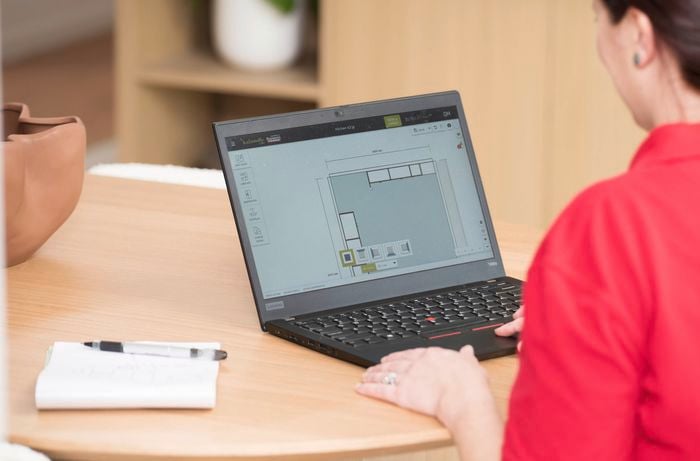 A Bunnings Team Member is using a laptop to design a kitchen layout with cabinetry on a 3D planning software.