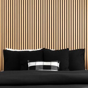 A room with floor lamp, bed and timber panels on the wall.