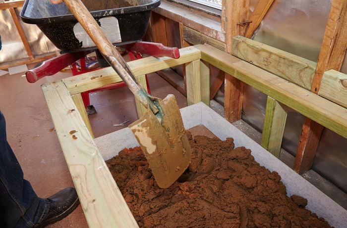 Person shovelling mortar into bath frame.