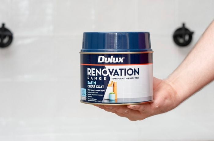 A person is holding a can of Dulux renovation range satin clear coat. 
