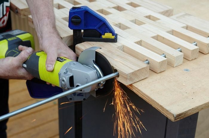 Person using handsaw to cut through metal bar.