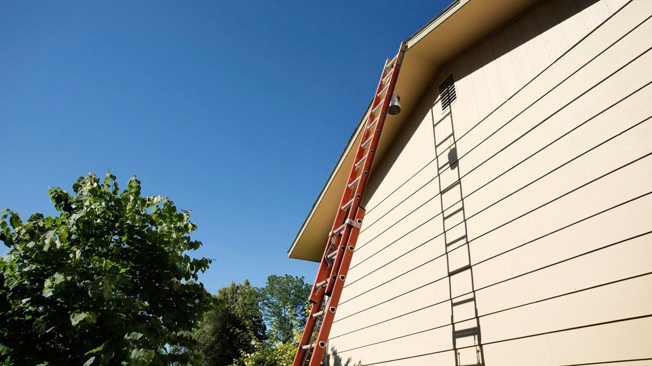 A tall extension ladder leaning against the exterior of a house