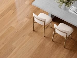 Light timber flooring beneath a grey table with two cream upholstered chairs and a vase of greenery.