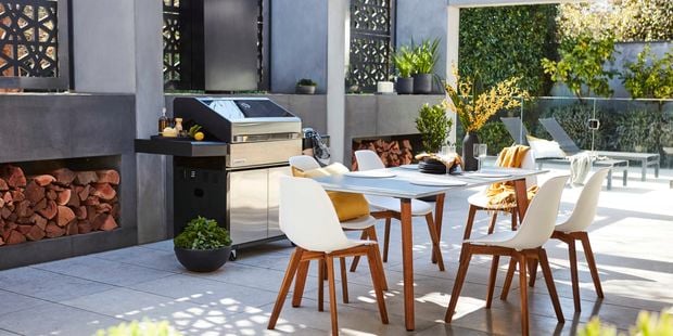 Outdoor setting including a table and chairs, and a barbecue.