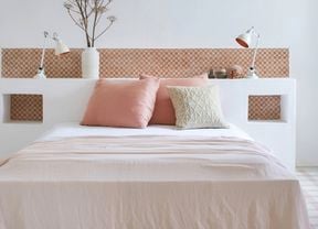 A modern bedroom featuring a built-in white headboard with decorative terracotta tiles, displaying the latest tile trends for stunning and functional spaces.