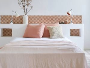 A modern bedroom featuring a built-in white headboard with decorative terracotta tiles, displaying the latest tile trends for stunning and functional spaces.
