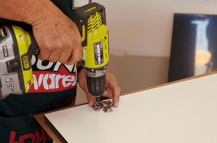 Person drilling hinges into doors