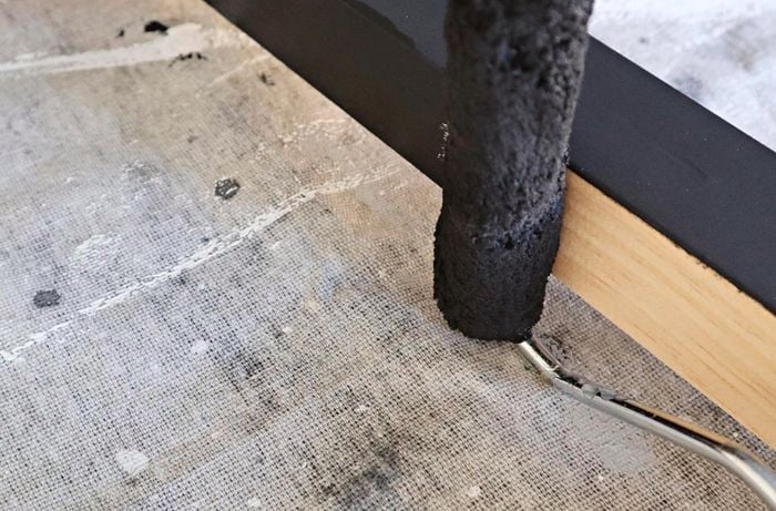 A length of timber being painted black
