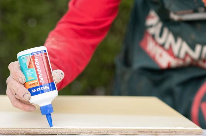 Wood glue being laid along the edge of a panel of wood