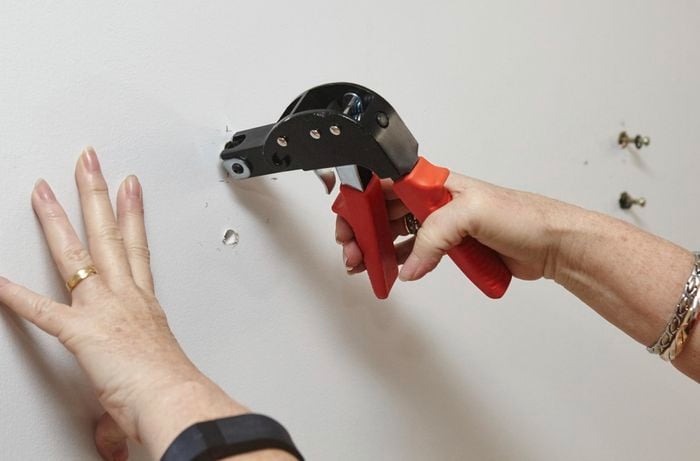 A person inserting wall anchors using a wall anchor setting tool