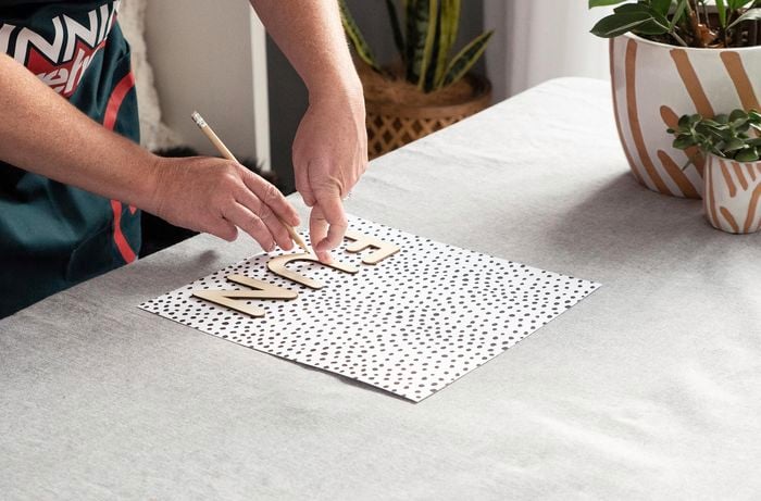 Person tracing the word FUN onto spotted paper.