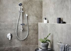Chrome showerhead in focus in bathroom 