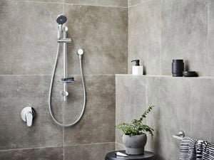 Chrome showerhead in focus in bathroom 
